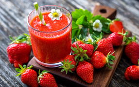 Strawberry smoothies with straw and fresh strawberries on a cutting board