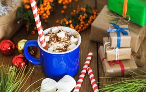 Сладкий напиток с маршмеллоу на столе с подарками на Новый год