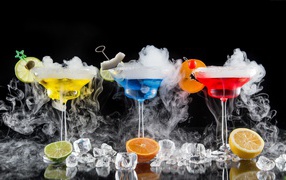 Три алкогольных коктейля с сухим льдом на черном фоне