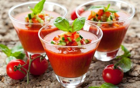Три стакана томатного сока с овощами на столе