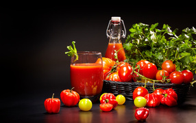 Томатный сок и свежие помидоры на столе на черном фоне