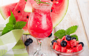 Watermelon juice with ice in a glass with fresh watermelon and blueberries