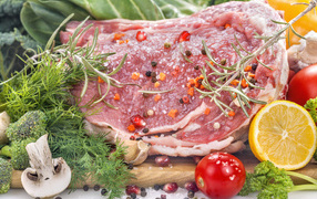 Кусок свежего мяса со специями и зеленью на разделочной доске