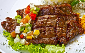 A piece of juicy roasted meat with vegetables and lettuce leaves