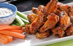 Appetizing Buffalo Wings with carrots, sauce and celery