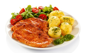 Appetizing chops with boiled potatoes and salad on a white plate