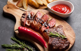 Appetizing juicy steak with sauce, red pepper and spices on the table