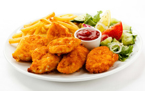 Chicken nuggets with ketchup, French fries and salad on a white plate