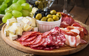 Мясная нарезка с сыром и оливками на разделочной доске