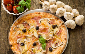 Fresh pizza with mushrooms on a table with garlic and tomatoes