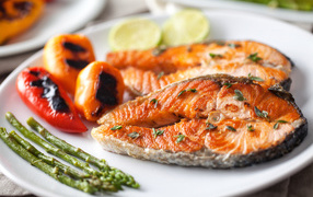 Два кусочка жареной красной рыбы с овощами 