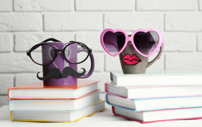 Две забавные чашки в очках стоят на книгах