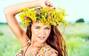 Нежная девушка шатенка с венком из полевых цветов на голове