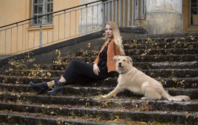 A young girl is sitting with a dog on the old steps