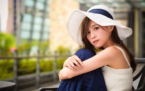 Красивая девушка азиатка в большой белой шляпе