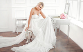 Красивая блондинка невеста в платье сидит на стуле