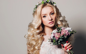 Красивая блондинка в свадебном платье с букетом цветов на сером фоне