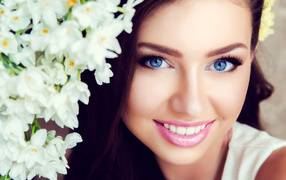 Beautiful blue-eyed brunette with delicate flowers of white orchids