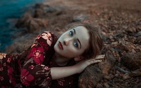 Красивая голубоглазая девушка лежит на камне 