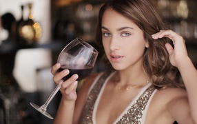 Beautiful blue-eyed girl with a glass of red wine in her hand