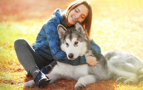 Красивая девушка брюнетка сидит на земле с собакой породы хаски