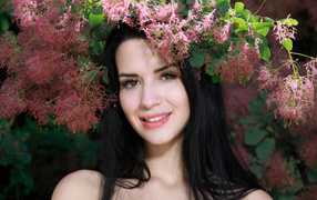 Красивая брюнетка стоит у цветущей ветки