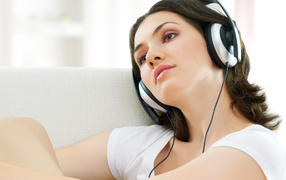 Beautiful gentle brown-haired listening to music on headphones