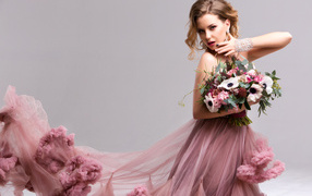Эффектная девушка в красивом розовом платье с букетом цветов в руках