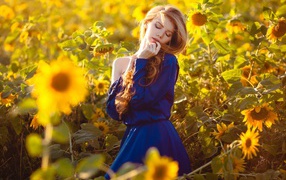 Красивая девушка в голубом платье в поле подсолнухов 