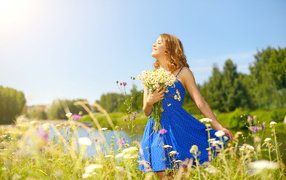 Красивая девушка в синем сарафане на поле с ромашками