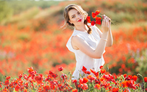 Красивая девушка в белом платье с букетом маков в руках