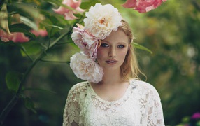 Красивая девушка в белом платье с большими пионами в волосах 