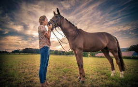 Beautiful girl kisses a horse under a beautiful sky