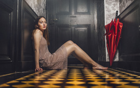 Красивая девушка модель с красным зонтом сидит на полу