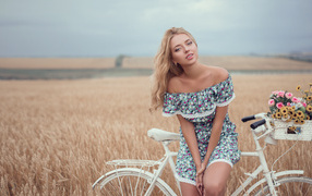 Красивая девушка на белом велосипеде в поле пшеницы
