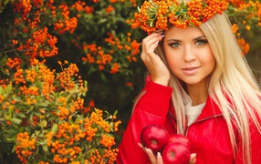 Красивая девушка с венком из рябины на голове и с красными яблоками в руках 