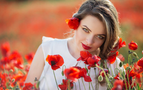 Beautiful girl with an expressive look on the field with red poppies