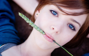 Красивая девушка с голубыми глазами с колоском во рту 