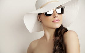 Красивая девушка в очках и большой белой шляпе