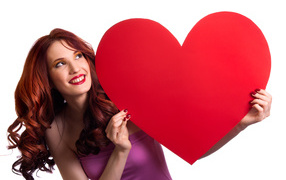 Красивая улыбающаяся девушка с большим красным сердцем в руках