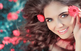 Красивая улыбающаяся девушка с розовыми цветами в волосах 
