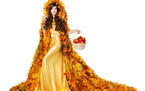 Красивая молодая девушка в плаще из желтых листьев с корзиной в руке