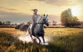 Красивая молодая девушка скачет на лошади по мокрой траве