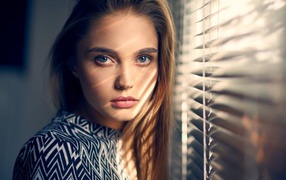 Blond girl with blue eyes by the window