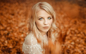 Blue-eyed blonde girl on a background of yellow foliage