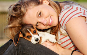 Убающаяся девушка шатенка с милым щенком на руках