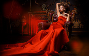 Девушка в красивом красном платье в кресле 