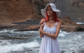 Red-haired girl in a hat and a white dress by the river