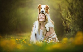 Smiling girl with dog sitting on the grass