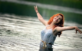 Улыбающаяся рыжеволосая девушка в воде 
